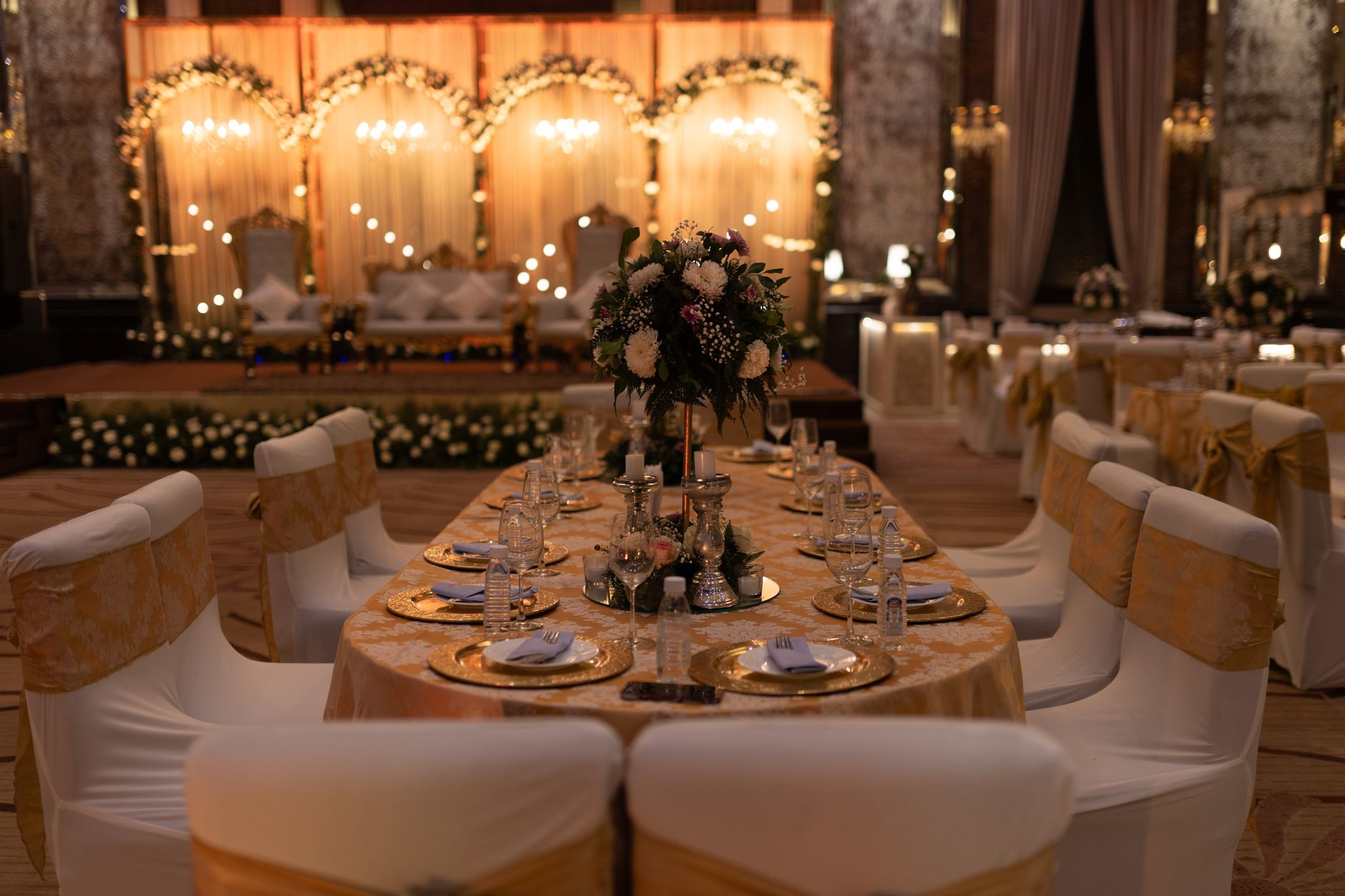 A beautifuly decorated wedding reception hall with floral arrangements and elegant lighting.