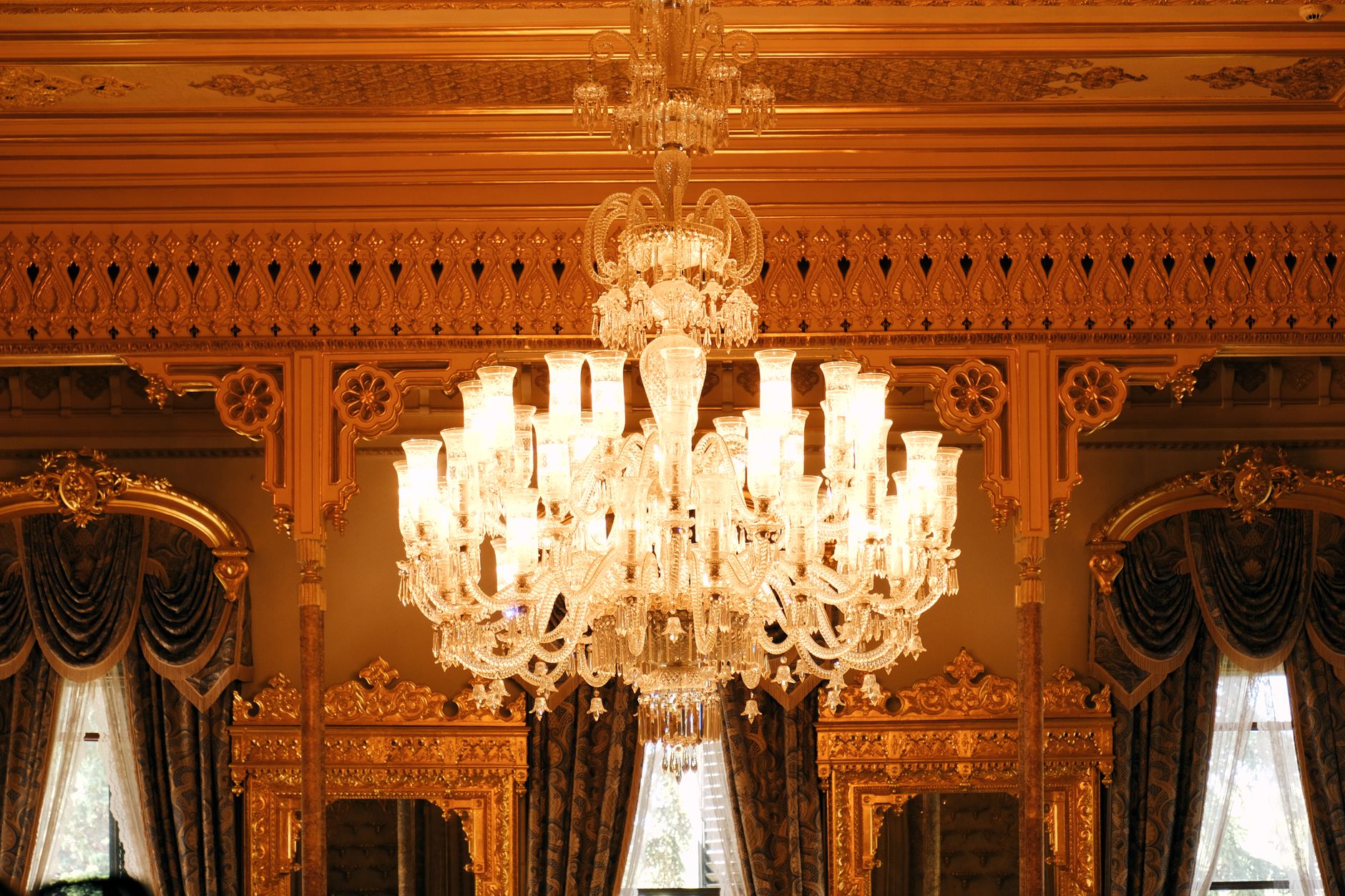 Opulent palace interior featuring a grand crystal chandelier illuminating elegant gold decor.