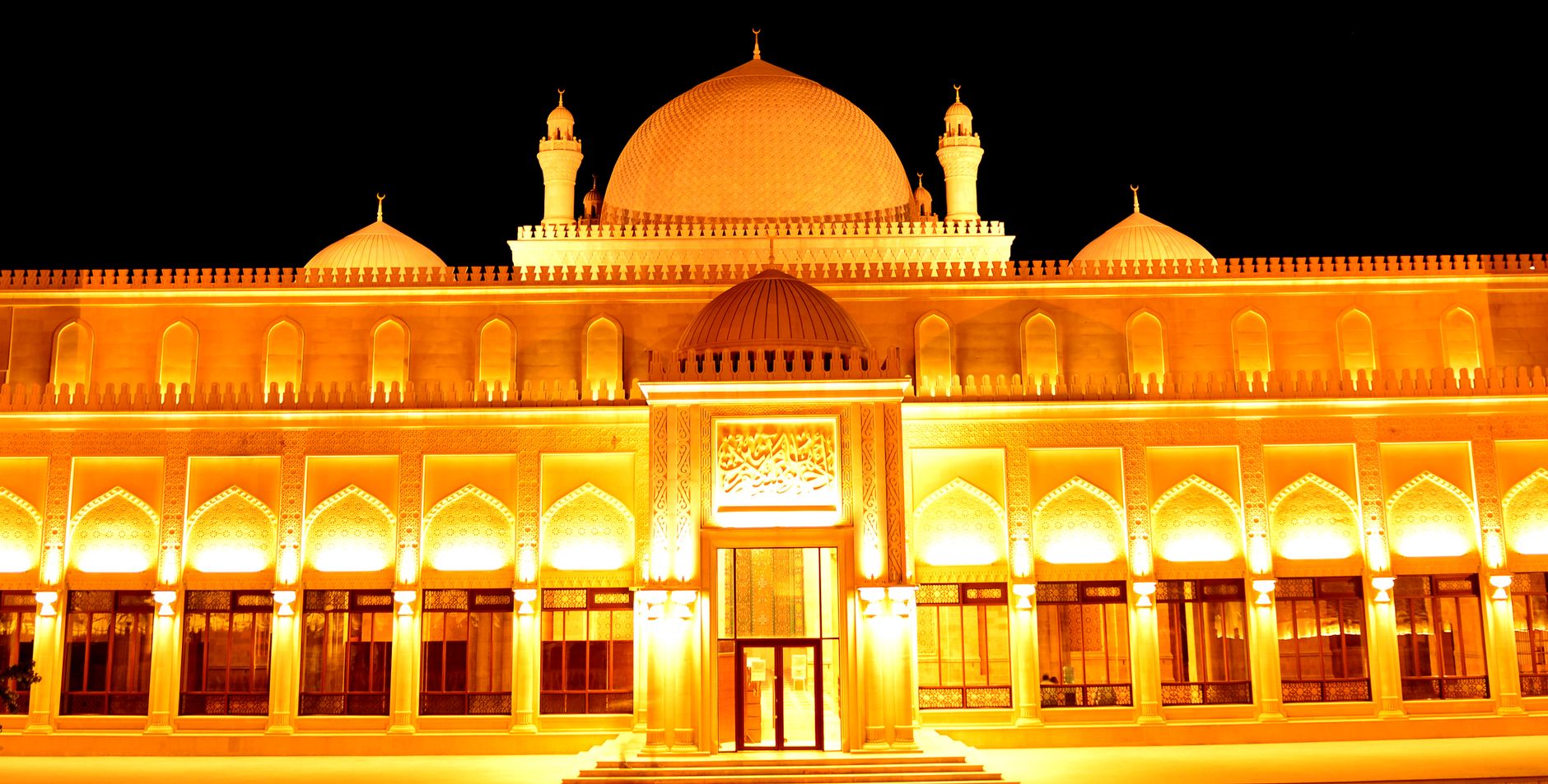A stunningly illuminated palace with golden light and domed architecture at night.